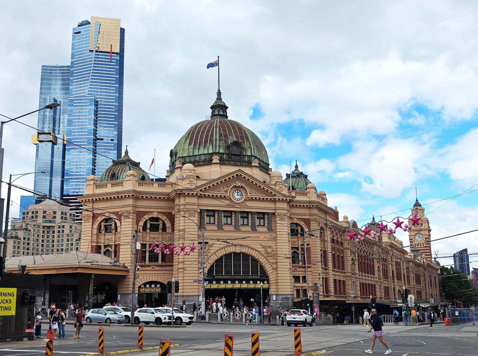 Iconic Flinders Street Station with Melbourne skyline on a vibrant day.
